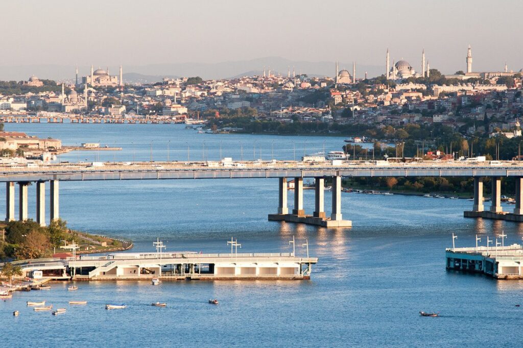 Historic bridge over river in vibrant city with diverse architecture and lush greenery.