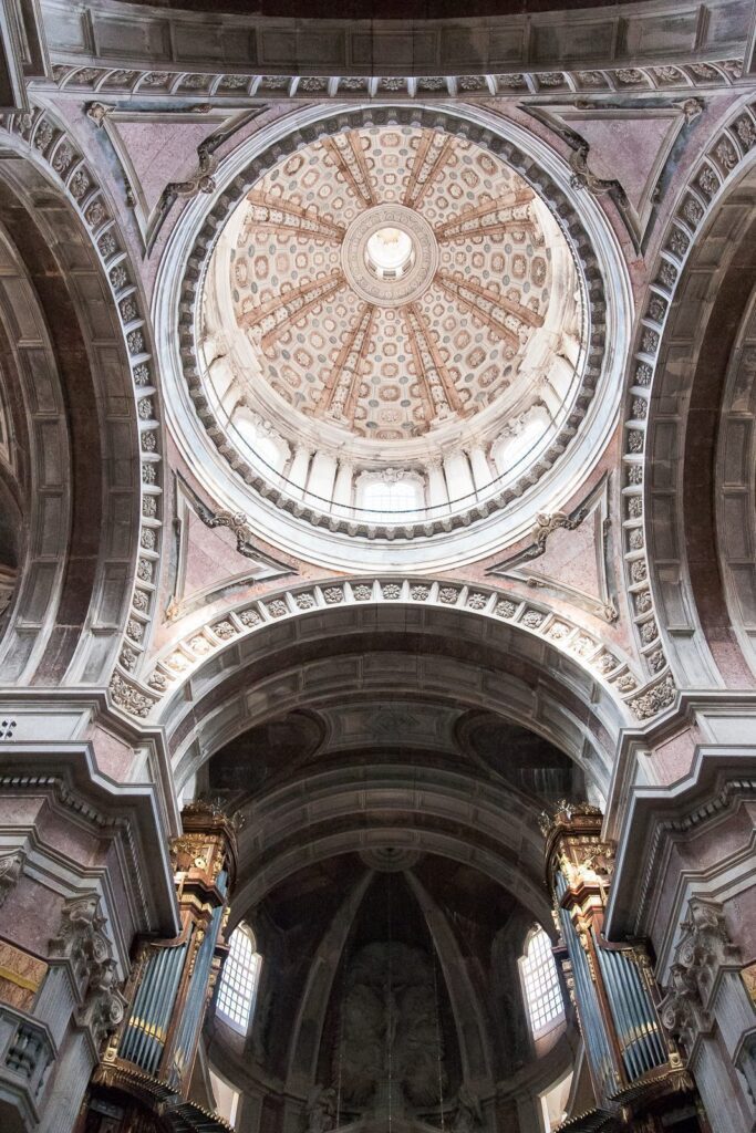 Ornate dome ceiling in grand cathedral with intricate geometric and floral designs, bathed in natural light.