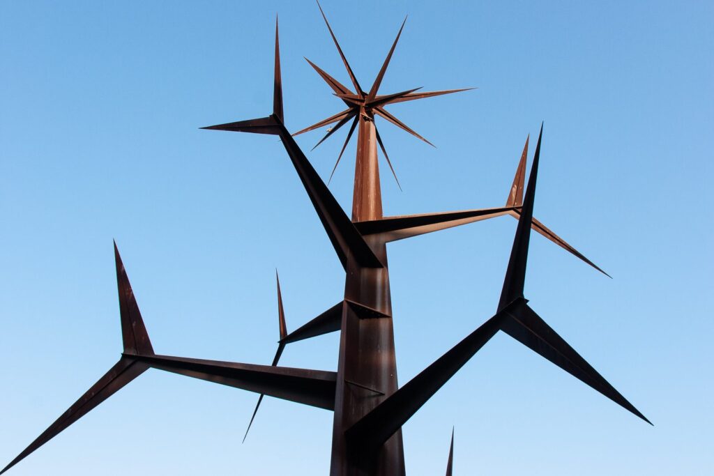 Rustic metal starburst sculpture contrasted against bright blue sky.