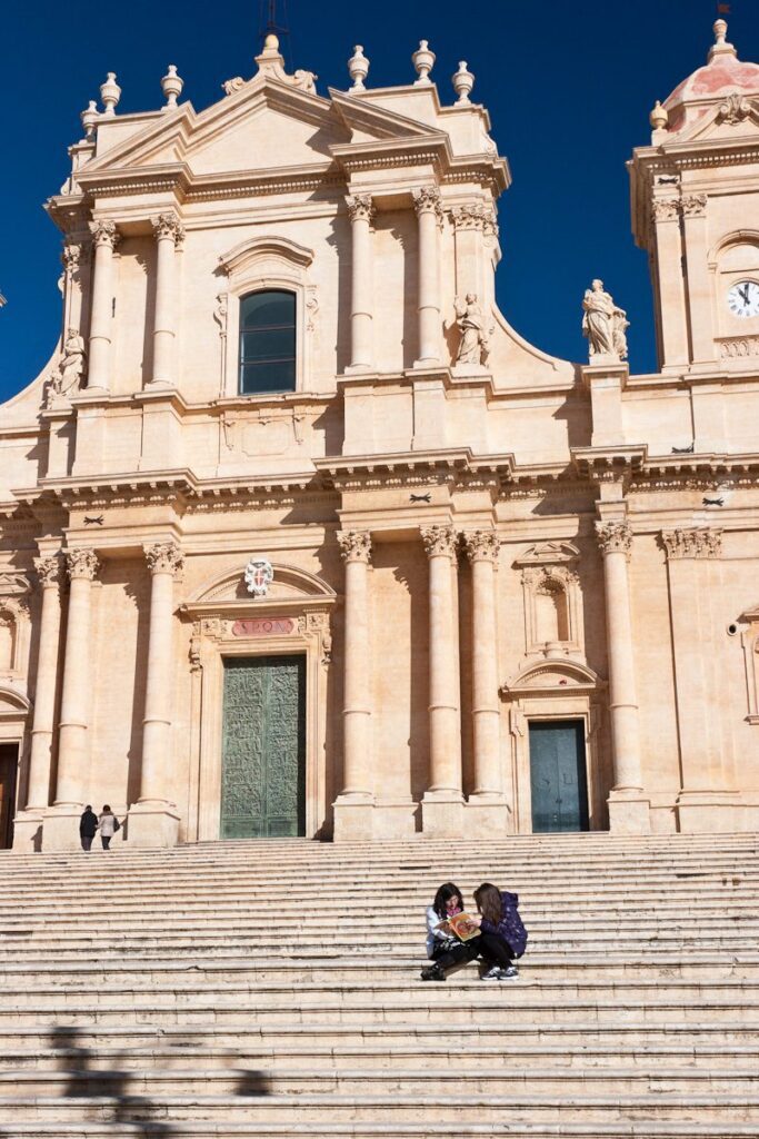 Historic cathedral steps with visitors in a grand baroque setting.