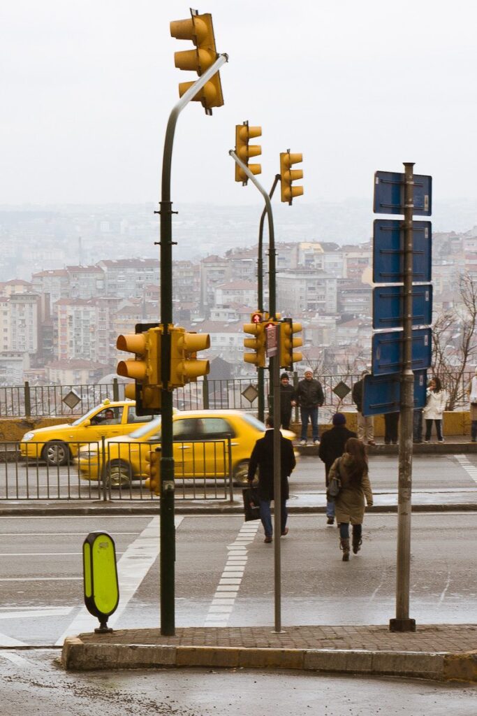 City intersection with pedestrians, taxis, and traffic lights on a cloudy day in the city.