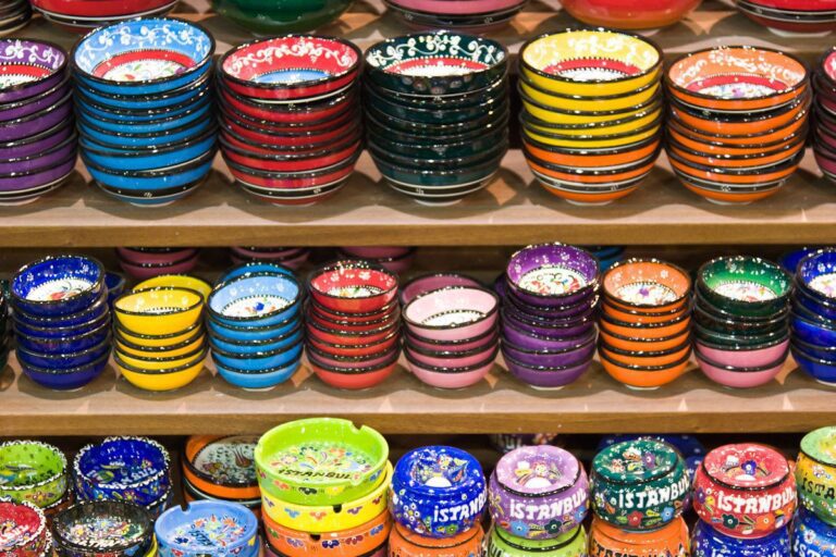 Colorful hand-painted ceramic bowls showcasing intricate designs and vibrant patterns on wooden shelves.