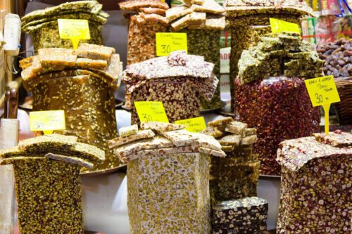 Indulgent nut brittles in vibrant market stall with colorful variety and handwritten tags.