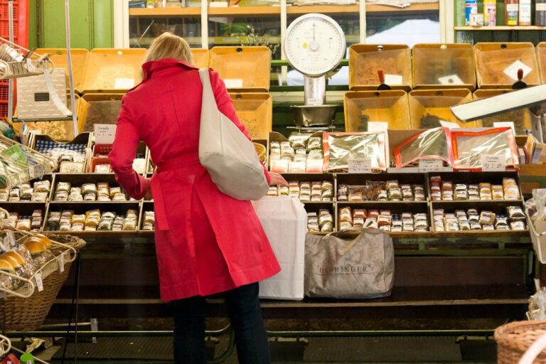 Woman shopping in cozy market, browsing goods in red coat.