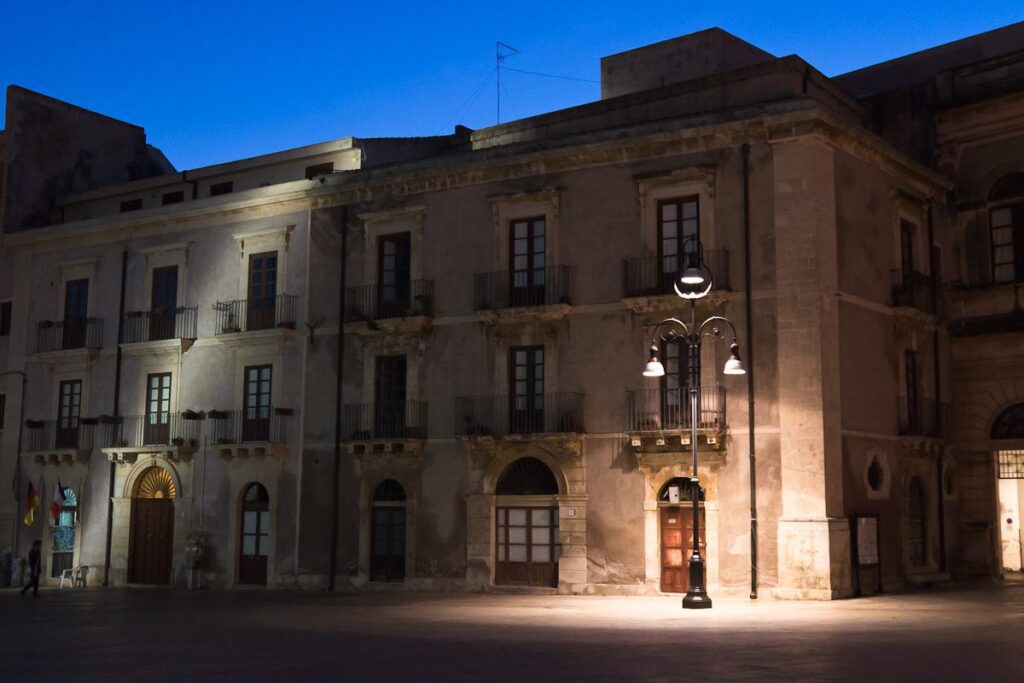 Twilight elegance: Historic European building illuminated by traditional street lamp at night.