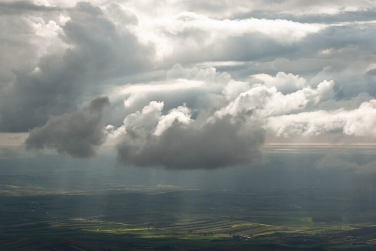 Cloudy Horizon: Vast landscape under dramatic skies with low-hanging clouds and beams of light.