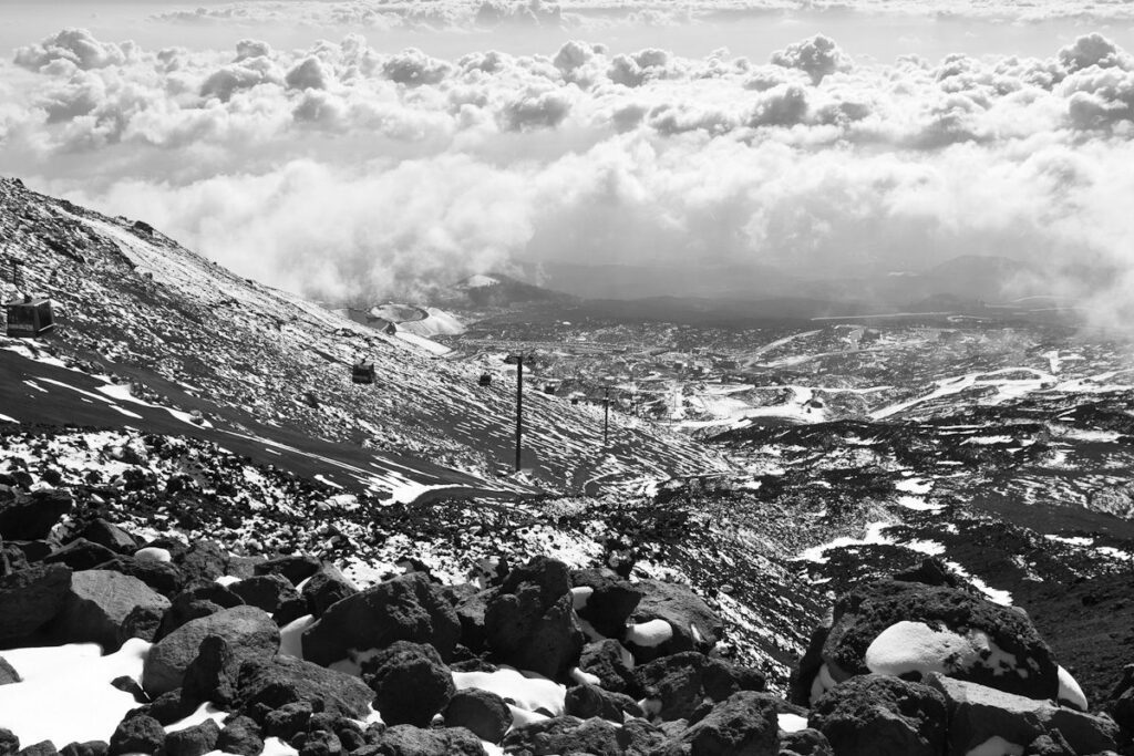 Snowy mountain landscape with ski lifts, rocks, and clouds in stunning black-and-white scenery.