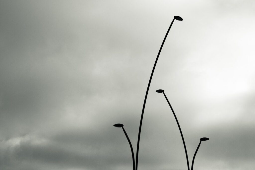 Moody streetlights against dramatic sky evoke contemplation and solitude.
