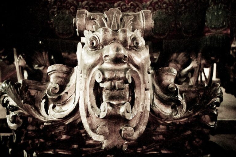 Intricately carved wooden figure with menacing face, detailed craftsmanship, and aged patina.
